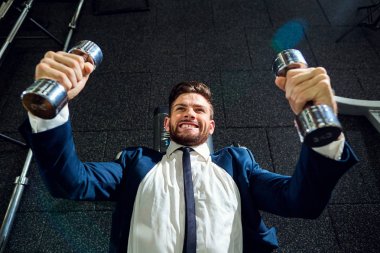 Spor salonunda dumbbells ile egzersizleri yapıyor işadamı