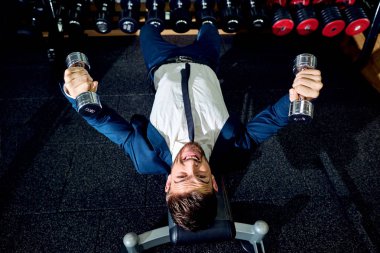 Spor salonunda dumbbells ile egzersizleri yapıyor işadamı