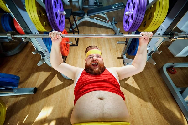 Grueso hombre haciendo ejercicios con una barra en el gimnasio — Foto de Stock