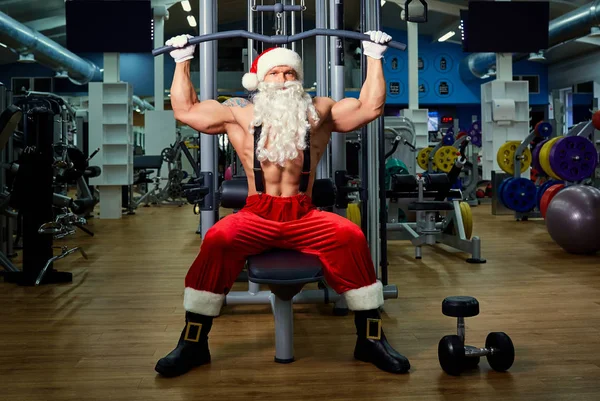 Santa Claus Bodybuilder training op de sportschool op Kerstmis. — Stockfoto