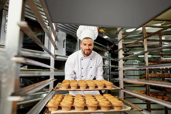 Ein Bäcker mit einem Blech Cupcakes. — Stockfoto