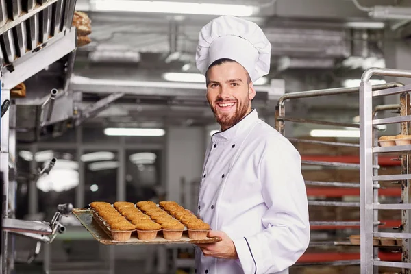 Ein Bäcker mit einem Blech Cupcakes. — Stockfoto