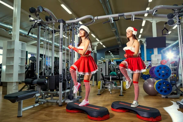 Noel Baba kostümleri Noel salonunda iki sportif kız — Stok fotoğraf