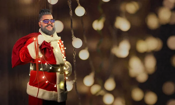 Santa Claus s zářící girlandy a brýle na Vánoce. — Stock fotografie