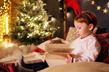 Küçük bir çocuk Noel Oda bir kitap okuyor.