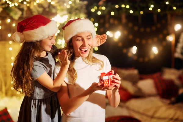 Mother and daughter in Santa hats give presents in a room  on Ch — Stock Photo, Image