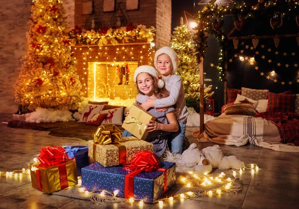 Šťastné děti v Santas klobouky s dárky v místnosti na Vánoce — Stock fotografie