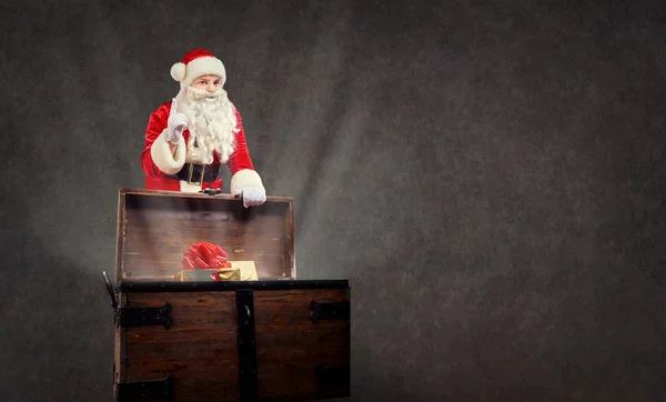 Noel Baba hediye boşaltmak arka plan üzerinde bir sandık ile. — Stok fotoğraf