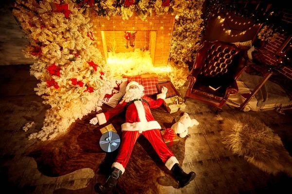Papai Noel está deitado bêbado no chão junto à lareira depois de C — Fotografia de Stock
