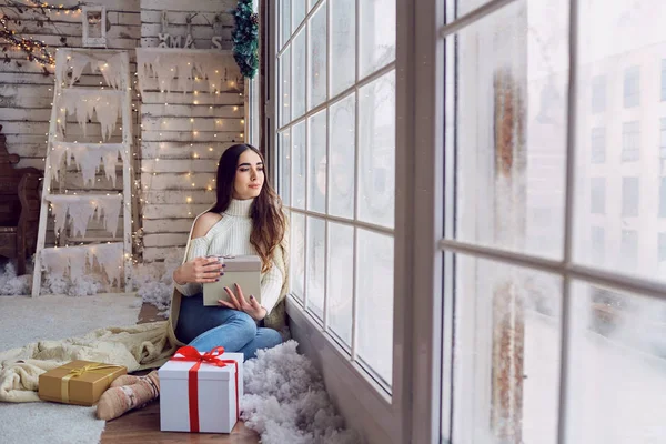 The girl at the window with gifts in the winter.