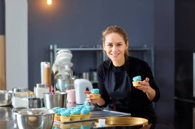 Bir tepsi cupcakes tutan pudra pasta kadın.