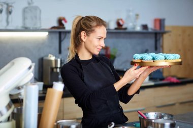 Bir tepsi cupcakes tutan pudra pasta kadın.