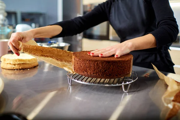 Las manos de una mujer confitera con costras de pastel en una mesa . — Foto de Stock