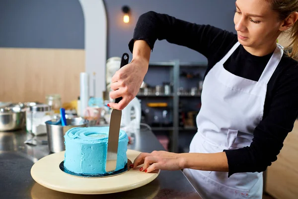 Una mujer pastelera cocinando un pastel en una mesa . — Foto de Stock