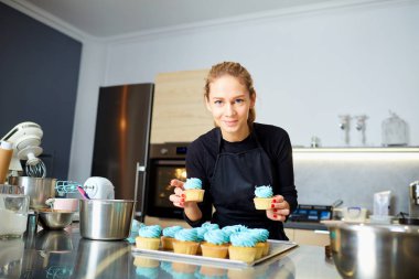Bir tepsi cupcakes tutan pudra pasta kadın.