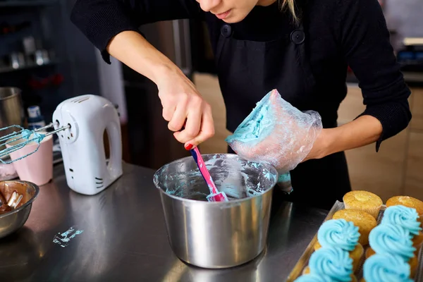 El confitero hace la crema para los cupcakes a la mesa de la cocina . — Foto de Stock