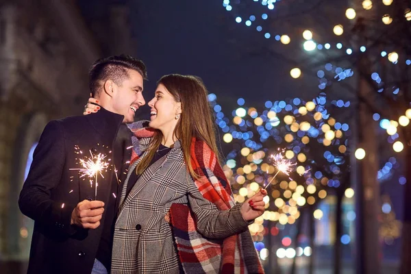 Una joven pareja riéndose con luces de Bengala en las manos . — Foto de Stock