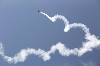 Aerobatic plane with a white smoke trail in sky. clipart