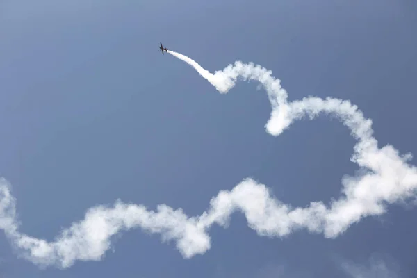 Aerobatic plane with a white smoke trail in sky. — Stock Photo, Image