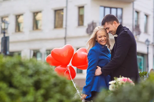 Egy szerető pár léggömbökkel ölelést, a város egy utcáján. — Stock Fotó