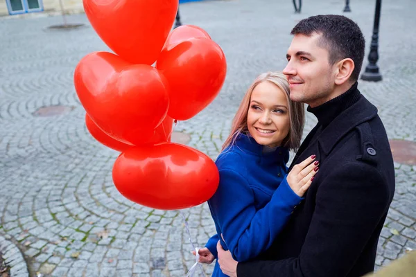 Una pareja amorosa con globos abrazos en una calle de la ciudad . — Foto de Stock