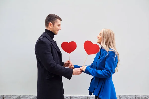 A loving couple in a coat with hearts in hands. — Stock Photo, Image