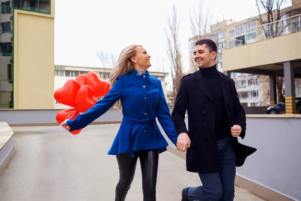 Любящая пара в пальто с воздушными шарами сердца в руках на cit — стоковое фото