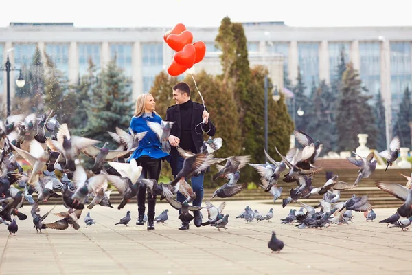 Milující pár v kabátě s balónky srdce ve svých rukou — Stock fotografie