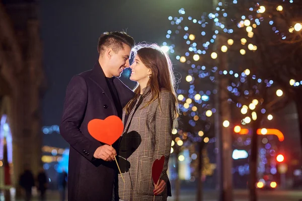 Een verliefde paar met een hart in de hand bij nacht bokeh licht. — Stockfoto