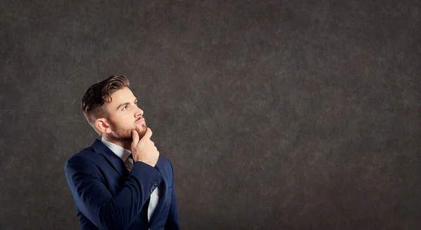 A young male businessman in a suit is thinking. — Stock Photo, Image