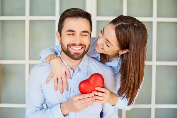 Um casal amoroso com um coração vermelho sorrindo . — Fotografia de Stock