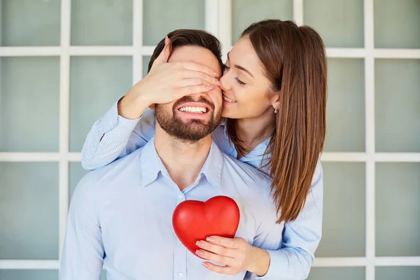 A loving couple with a red heart smiling. — Stock Photo, Image