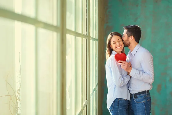 Um casal amoroso com um coração vermelho sorrindo . — Fotografia de Stock