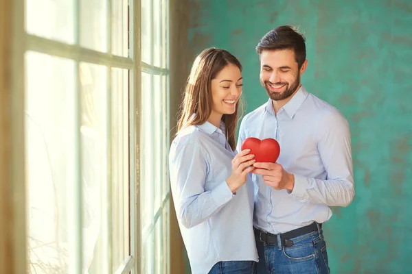 Um casal amoroso com um coração vermelho sorrindo . — Fotografia de Stock