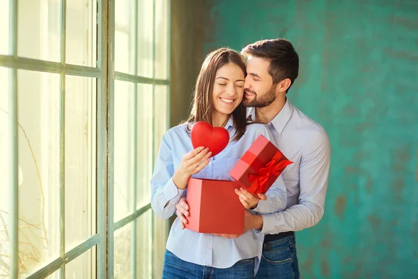 A loving couple with a red heart smiling. — Stock Photo, Image