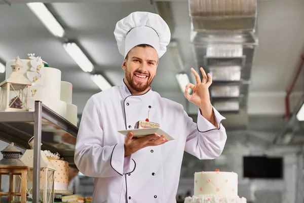 Pasticciere uomo con una torta in mano nella pasticceria . — Foto Stock