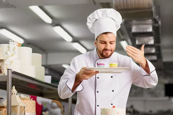 Hombre pastelero con un pastel en sus manos en la pastelería . — Foto de Stock