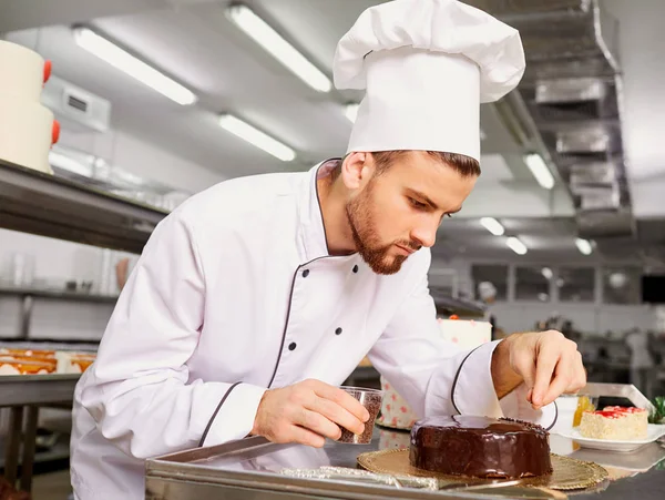 Hombre pastelero con un pastel en sus manos en la pastelería . — Foto de Stock