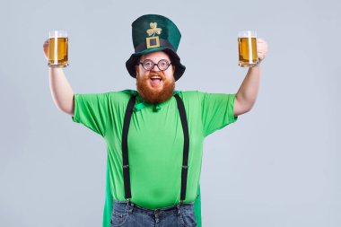 St. Patricks elbiseli sakallı şişman bir adam bir m ile gülümsüyor