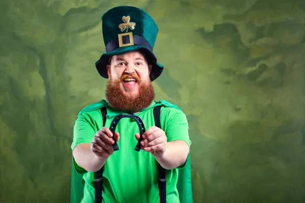 En fet man med ett skägg i kostym av St. Patrick ler en häst — Stockfoto