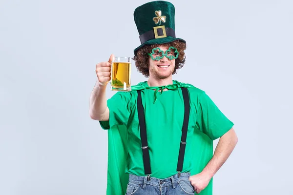 A young curly-haired man in the suit of St. Patrick with a mug o — Stock Photo, Image