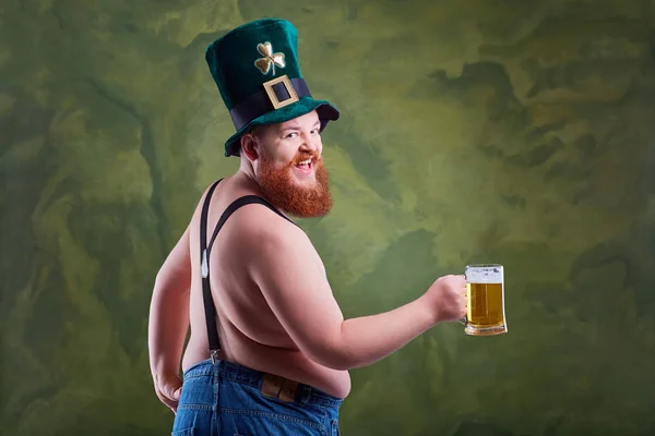 En fet man med ett skägg i St. Patricks kostym ler med m — Stockfoto