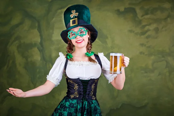 Egy lány, egy korsó sör jelmezre St. Patrick mosolyog. — Stock Fotó