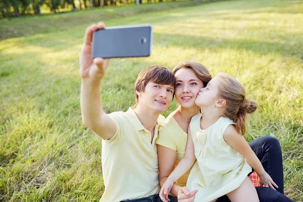 Glücklich lächelnde Familie wird im Park fotografiert — Stockfoto