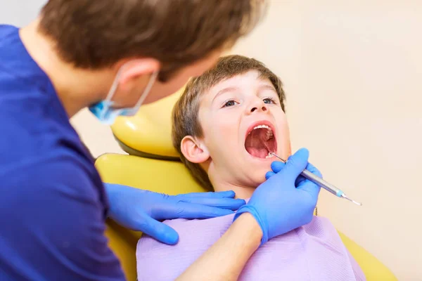 O dentista verifica os dentes de um homem adolescente . — Fotografia de Stock