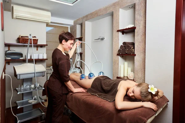 Une femme allongée en train de faire un massage au rouleau sous vide dans la cabine du spa — Photo