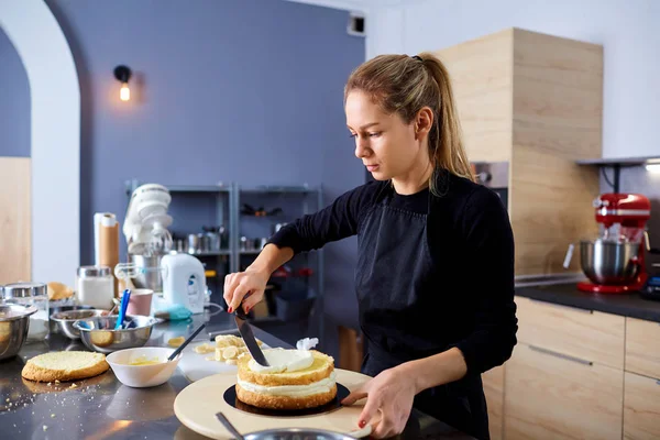 A confectioner woman makes  cake in the kitchen.