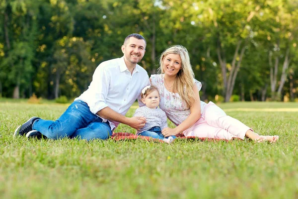 Familia feliz en un parque en otoño de verano. Madre, padre y bebé — Foto de Stock