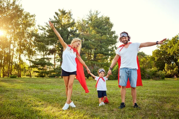 Boldog család ruhák a szuperhősök a parkban. — Stock Fotó