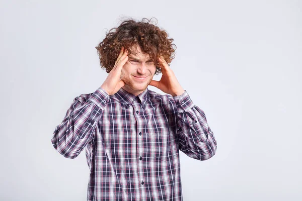 Krullend jonge man die zijn hoofd met negatieve emoties op zijn f — Stockfoto